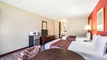 A hotel room with two beds, a desk with a TV, a microwave, and a small seating area.
