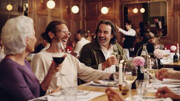 Eine Gruppe von Menschen speist in einem Restaurant mit Holzvertäfelung und runden Leuchten.