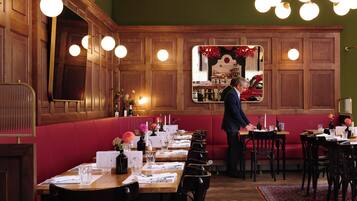 Un restaurante con paneles de madera, cabinas rojas y un hombre de pie junto a la barra.