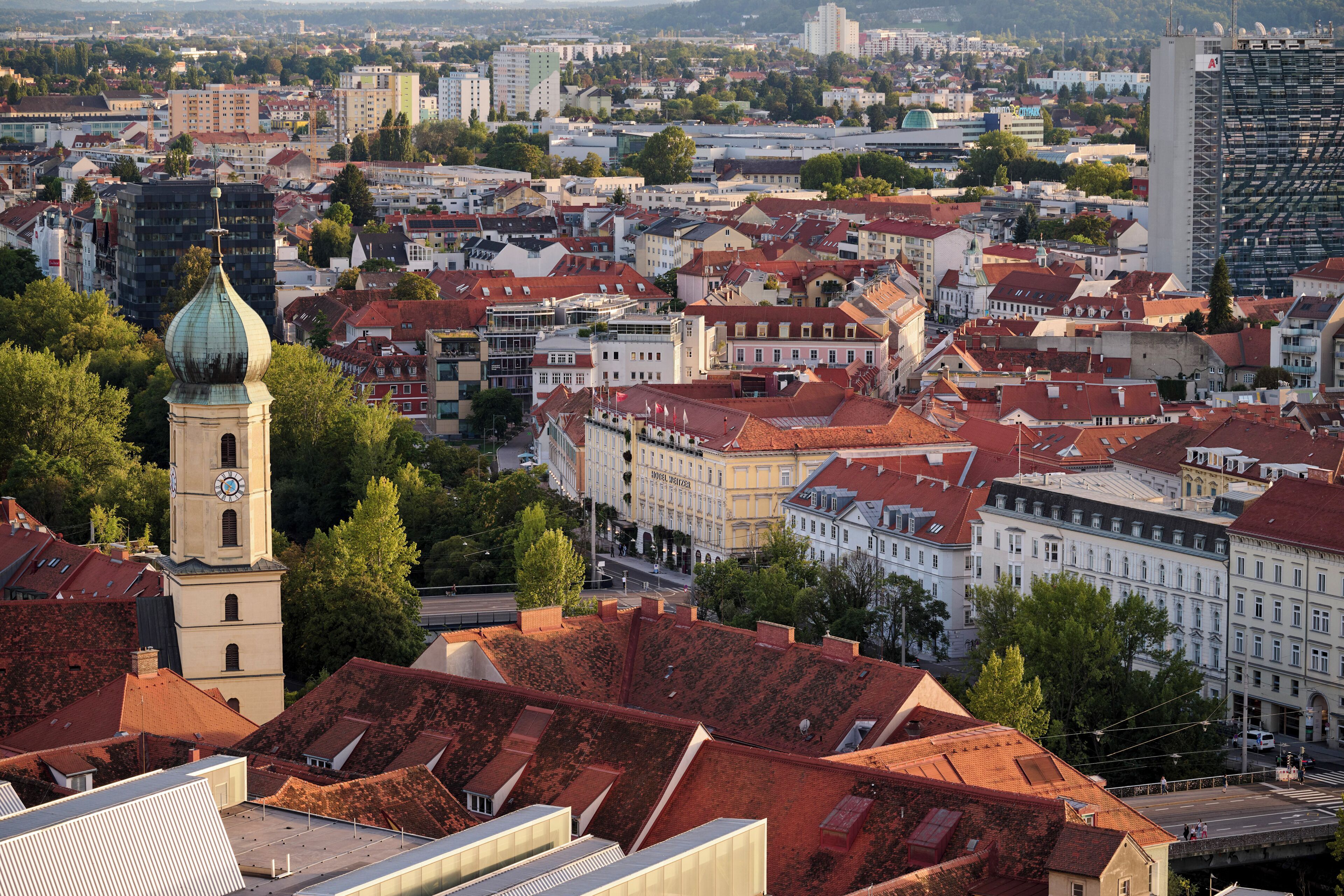 A cityscape with historic buildings, a prominent clock tower, and a modern high-rise.