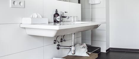 A modern bathroom with a white sink, mirror, and wooden vanity.