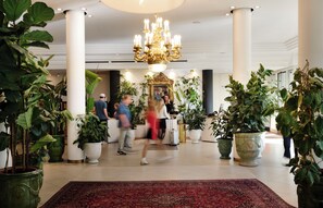 A lobby with a chandelier, potted plants, a reception desk, and a red carpet. - Hotel Weitzer Graz (Graz)