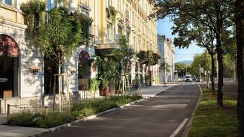 A street with a hotel named 'HOTEL WIELTER' on the left, featuring a row of windows with plants and a clear road.
