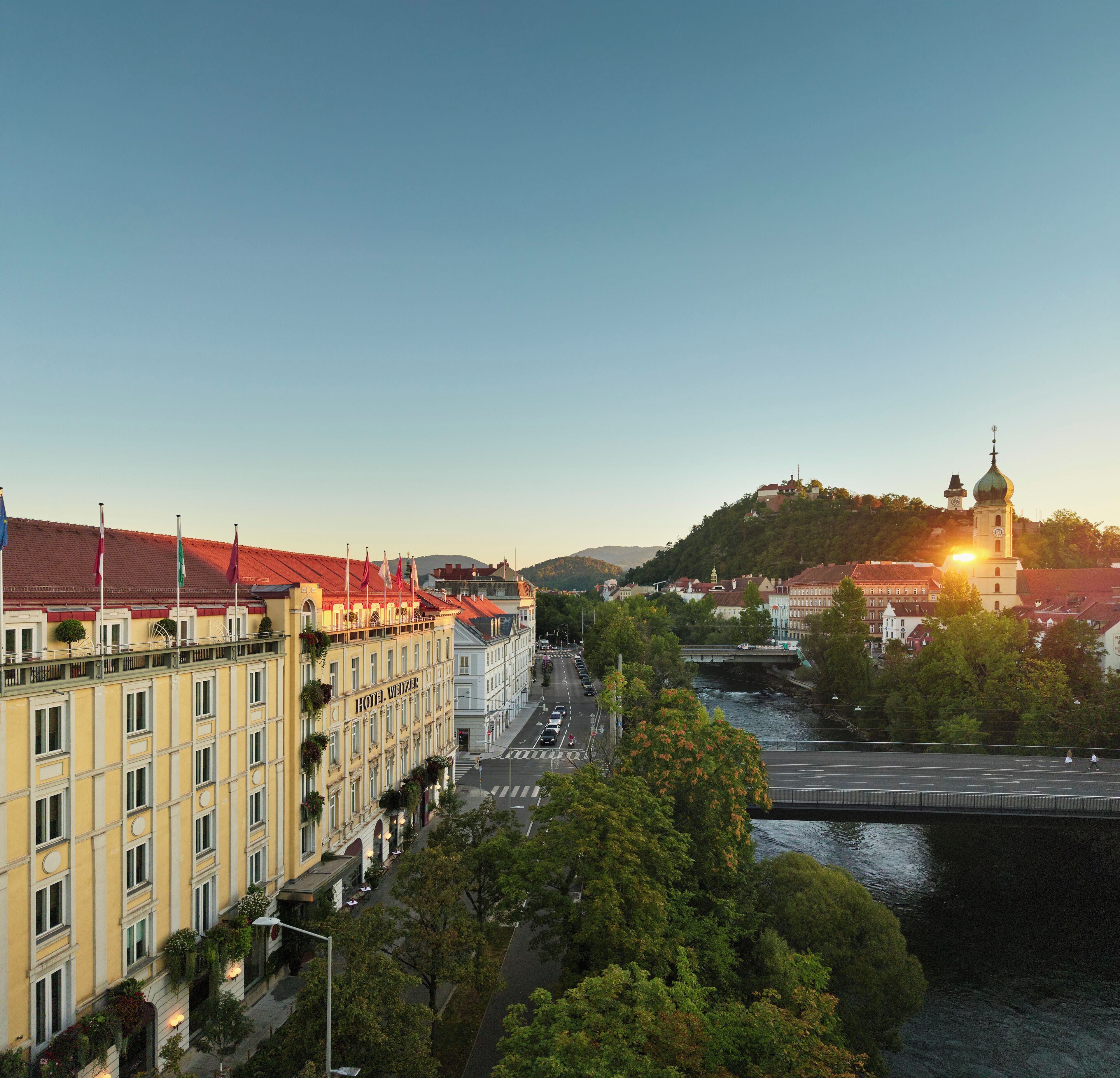 Ein Hotel mit rotem Dach, einem Glockenturm und einem Fluss im Hintergrund.