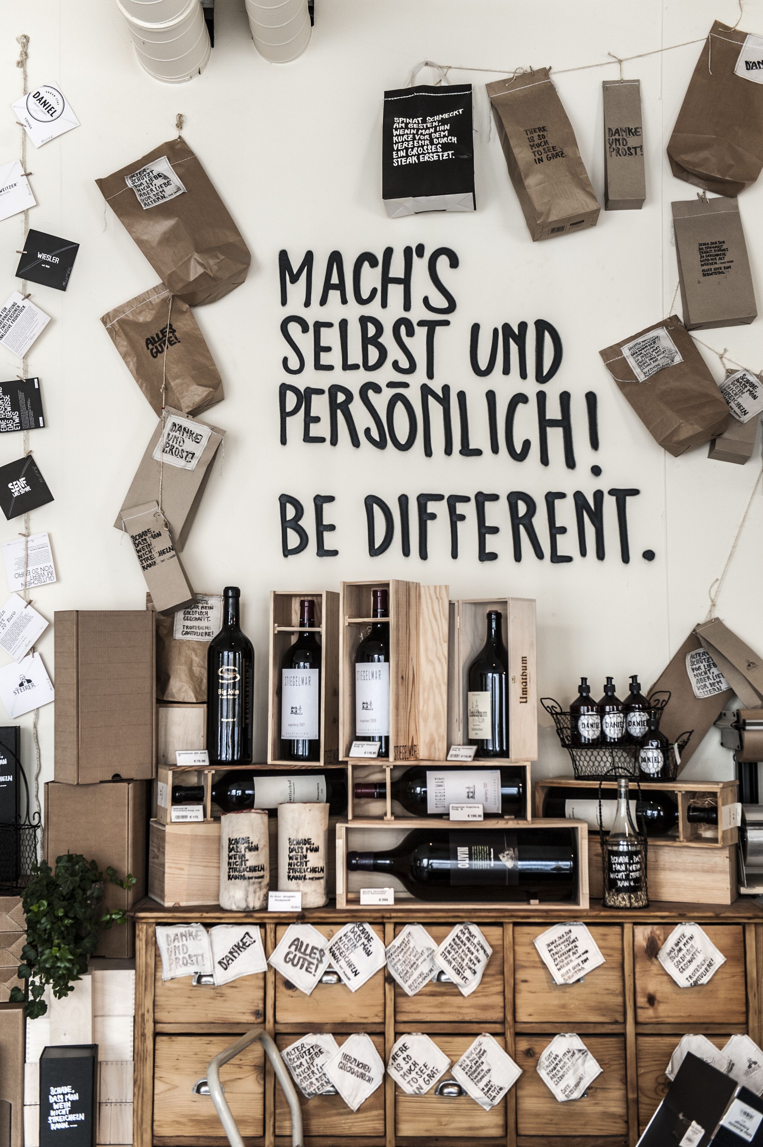 A wall with a motivational quote and various items including wine bottles and paper bags.