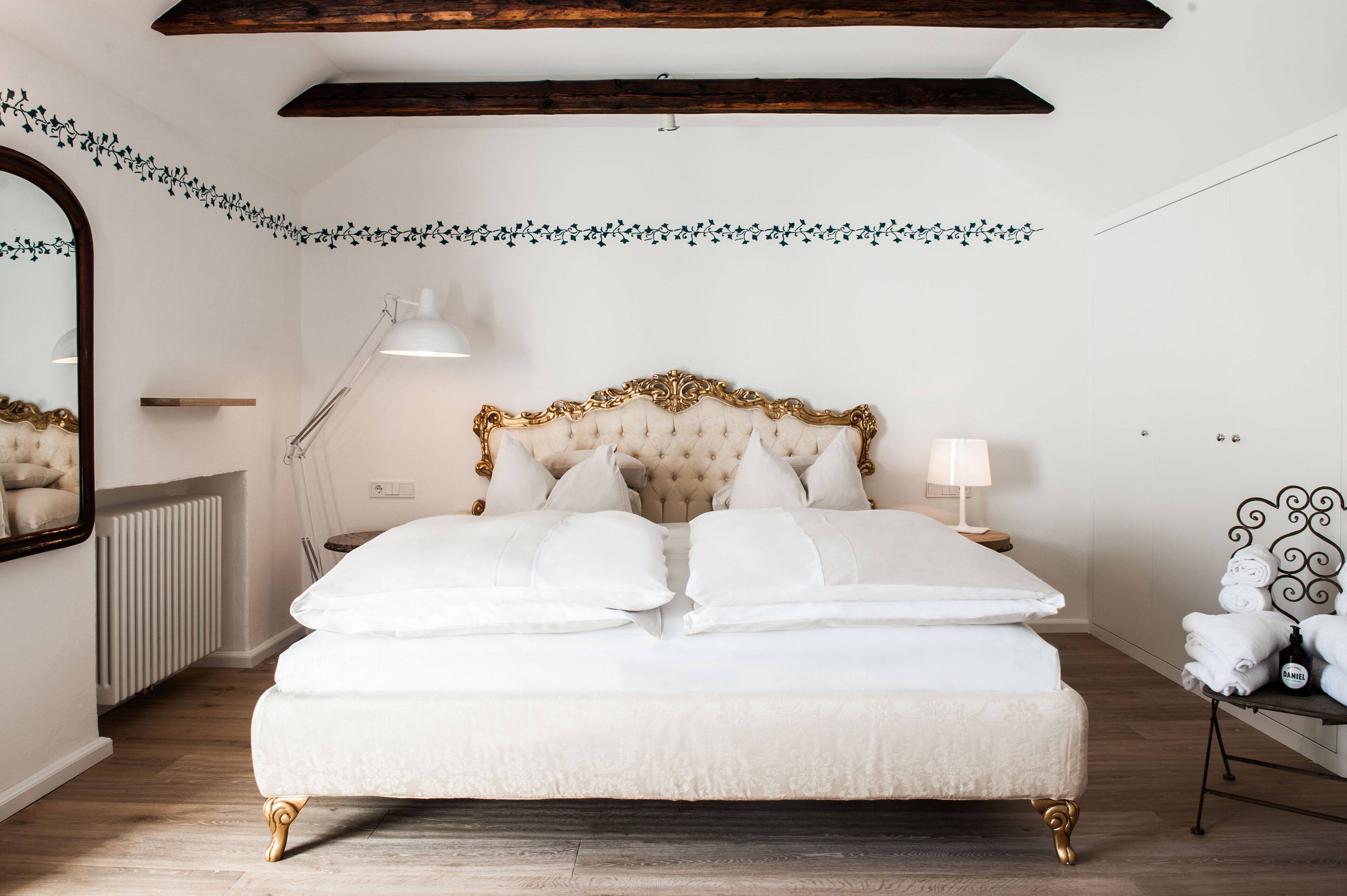 Une chambre à coucher avec un grand lit, une table de chevet avec une lampe, un radiateur et un miroir décoratif.