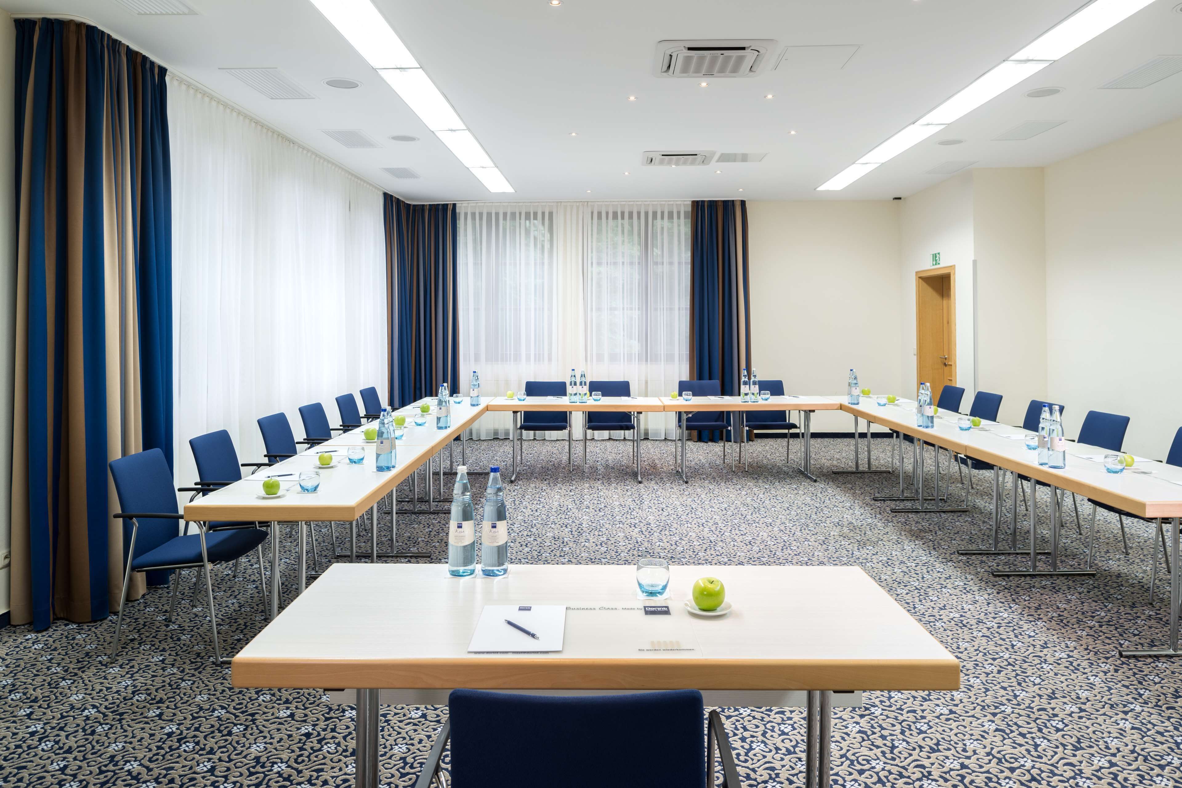 A conference room with a long table, chairs, water bottles, and a whiteboard.