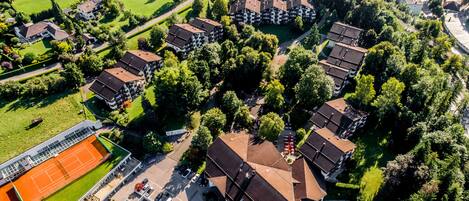Vista aérea de un área residencial con varios edificios de apartamentos, una cancha de tenis y un estacionamiento.