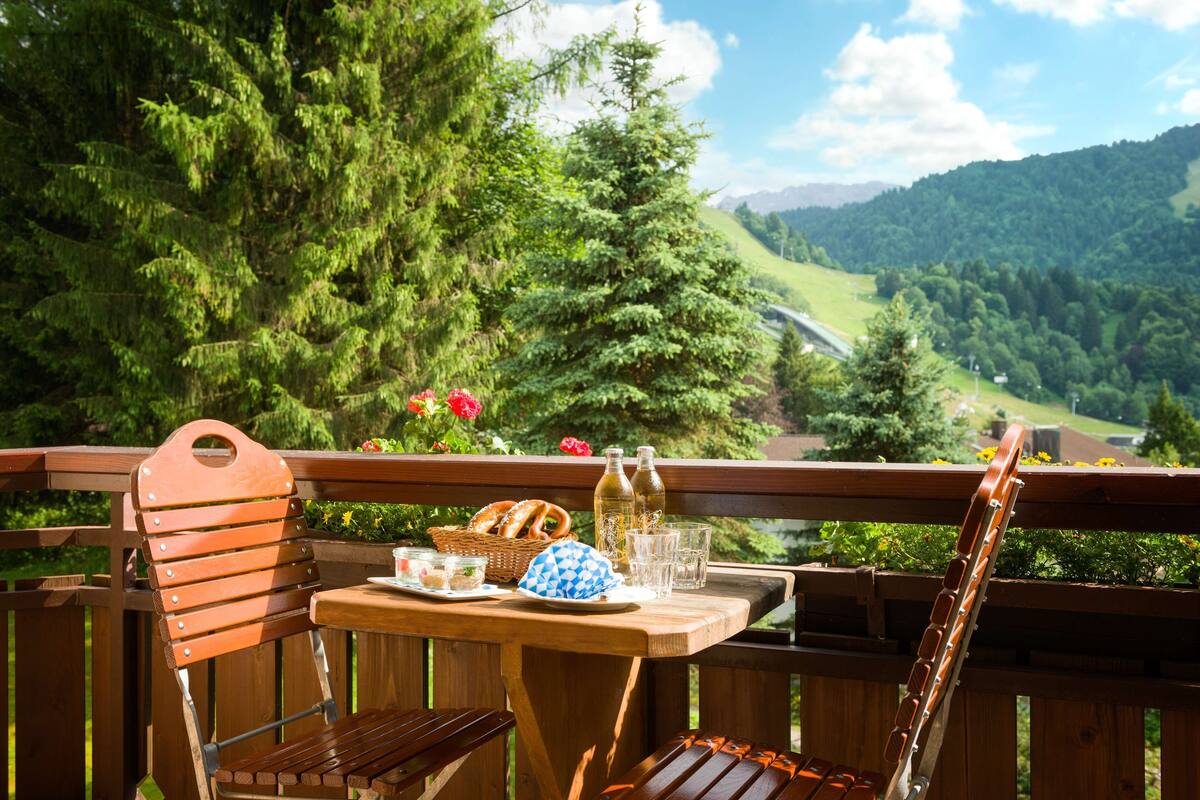 A wooden deck with a table set for a meal, overlooking a lush valley.