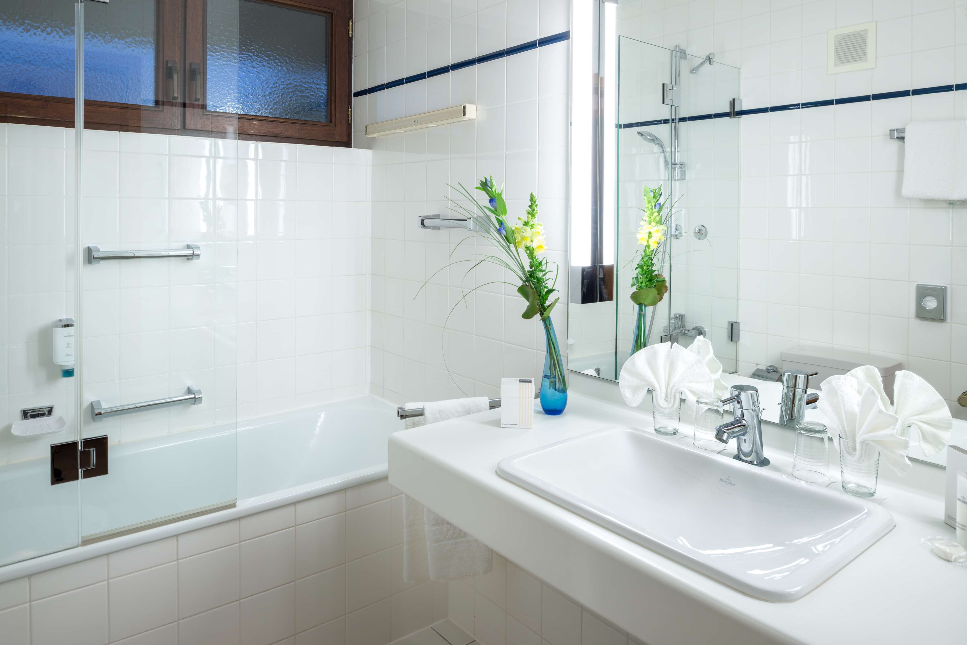 A modern bathroom with a glass shower enclosure, a white sink, and a mirror.