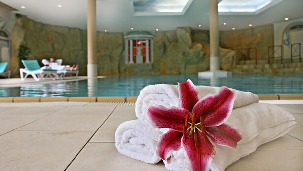 A pool area with a view of the interior, including a stone wall and a pool. - Dorint Sporthotel Garmisch-Partenkirchen (Garmisch-Partenkirchen)