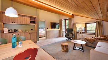 Un interior moderno con techo de madera, una zona de comedor con mesa y sillas, un sofá, un televisor y una ventana con cortinas.