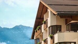 A multi-story hotel with balconies, surrounded by lush greenery and mountains. - Dorint Sporthotel Garmisch-Partenkirchen (Garmisch-Partenkirchen)