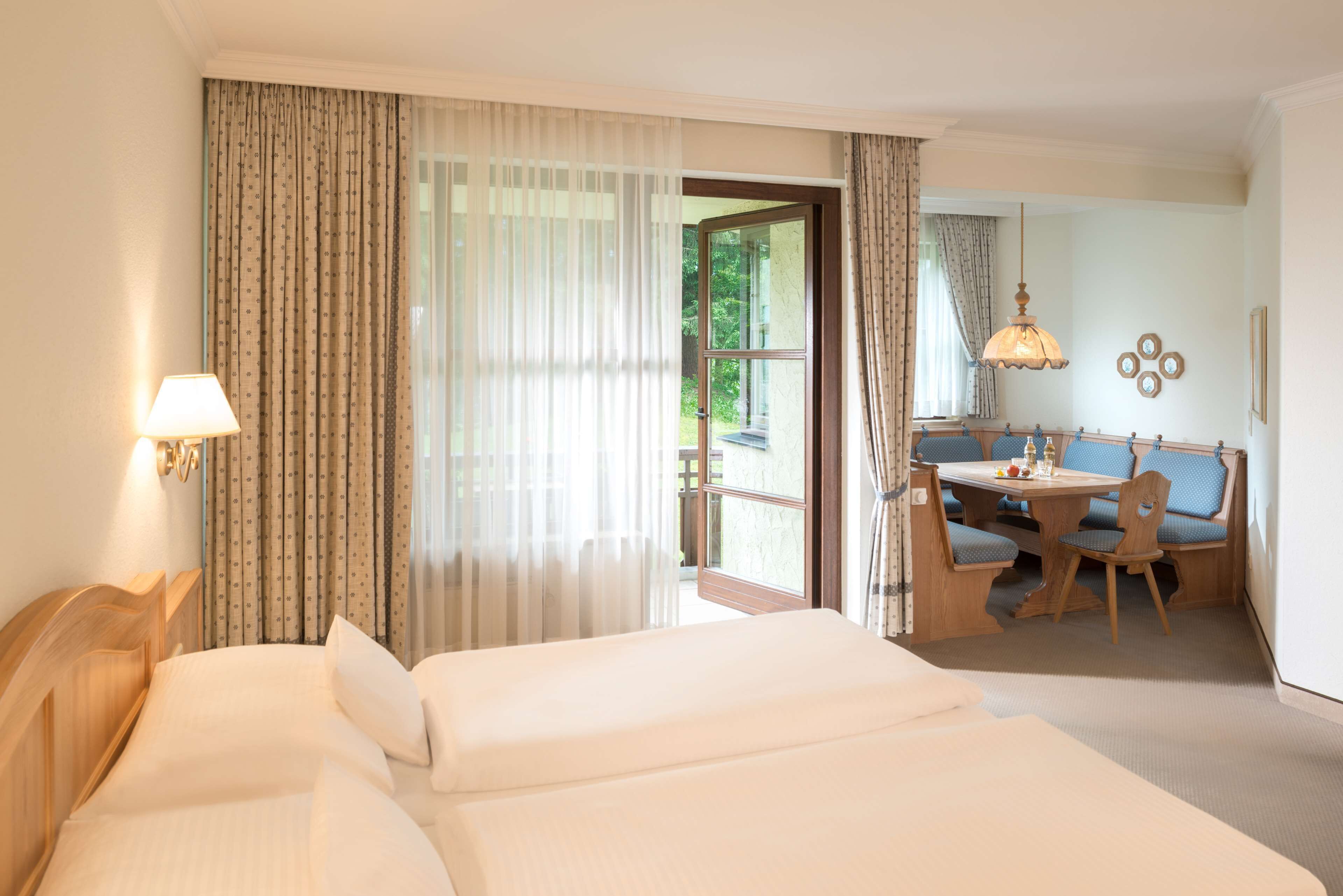 A hotel room with a bed, a desk, and a dining area.