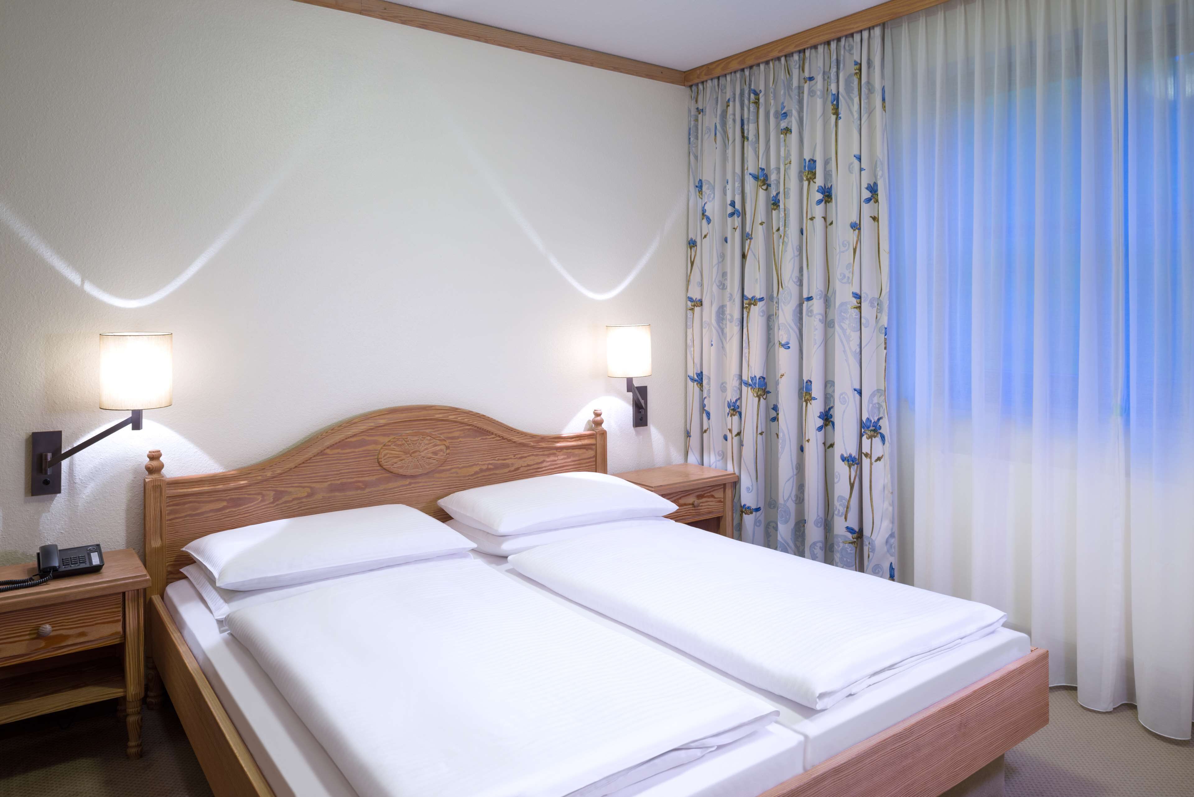 Un lit double avec deux tables de chevet, chacune équipée d’une lampe et d’un téléphone.
