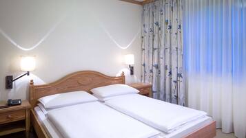 Ein Doppelbett mit zwei Nachttischen, auf jedem ein Lampenschirm und ein Telefon.