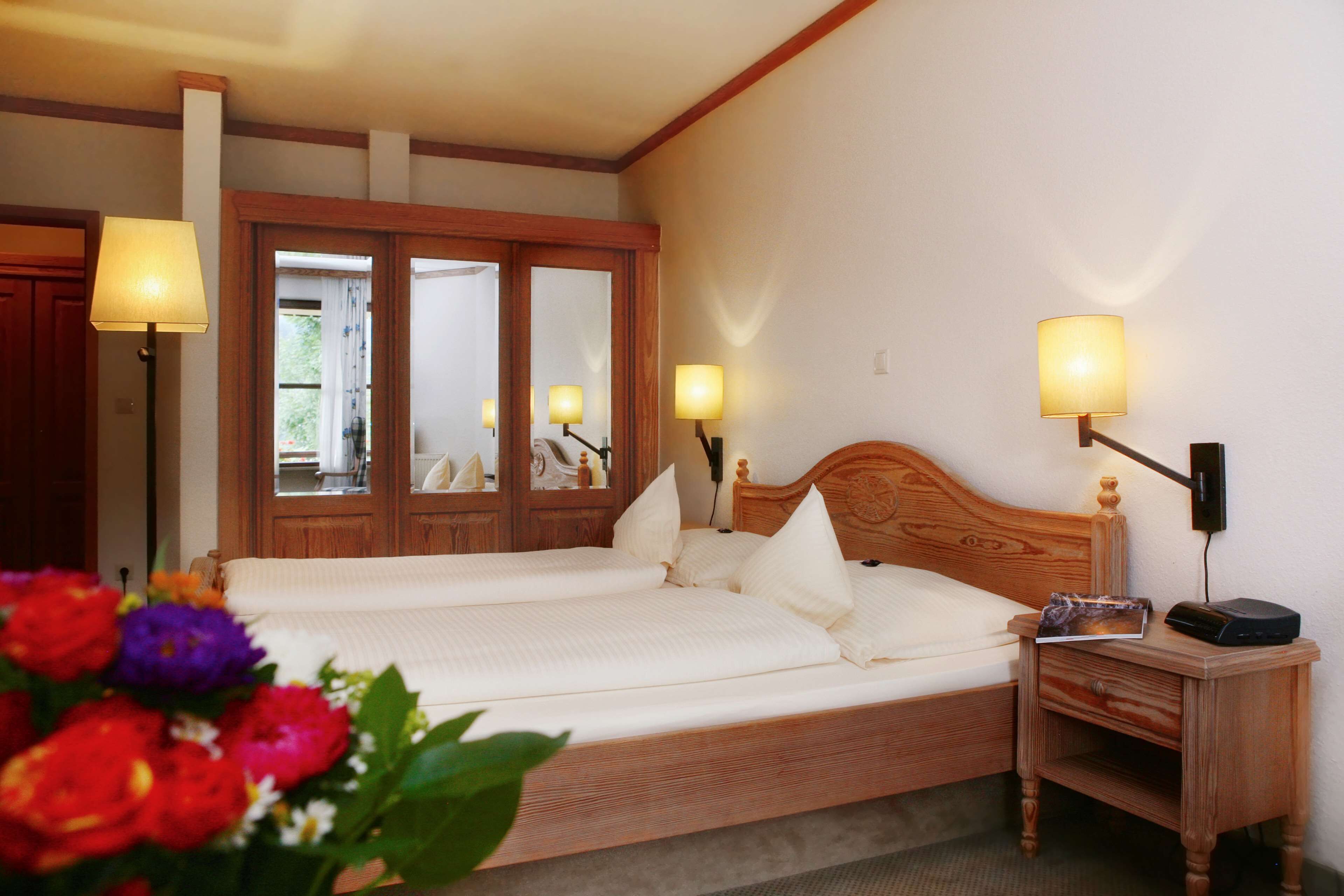 Ein Hotelzimmer mit einem hölzernen Bett, zwei Nachttischlampen, einem Nachttisch und einem Spiegel.
