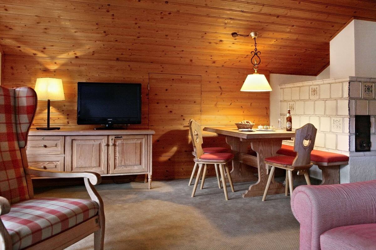 Une pièce chaleureuse avec des murs en bois, une télévision, une table à manger avec des chaises et une cheminée.