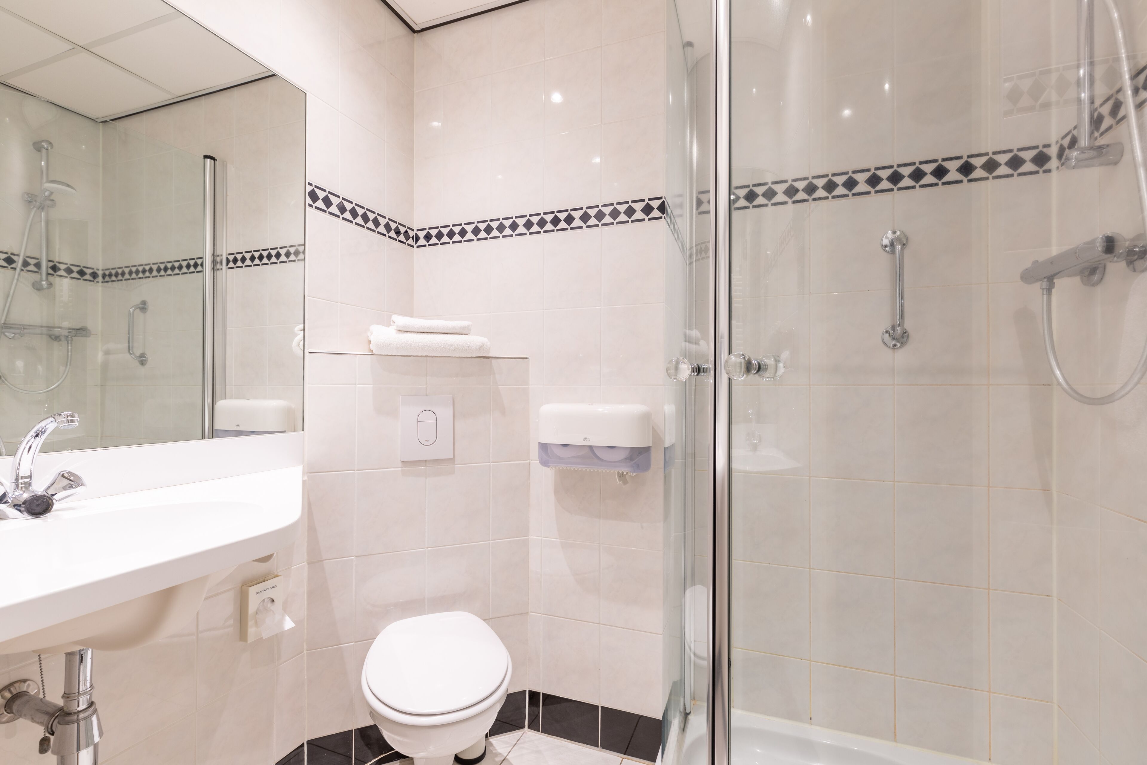 Un baño moderno con ducha de vidrio, lavamanos blanco y retrete.