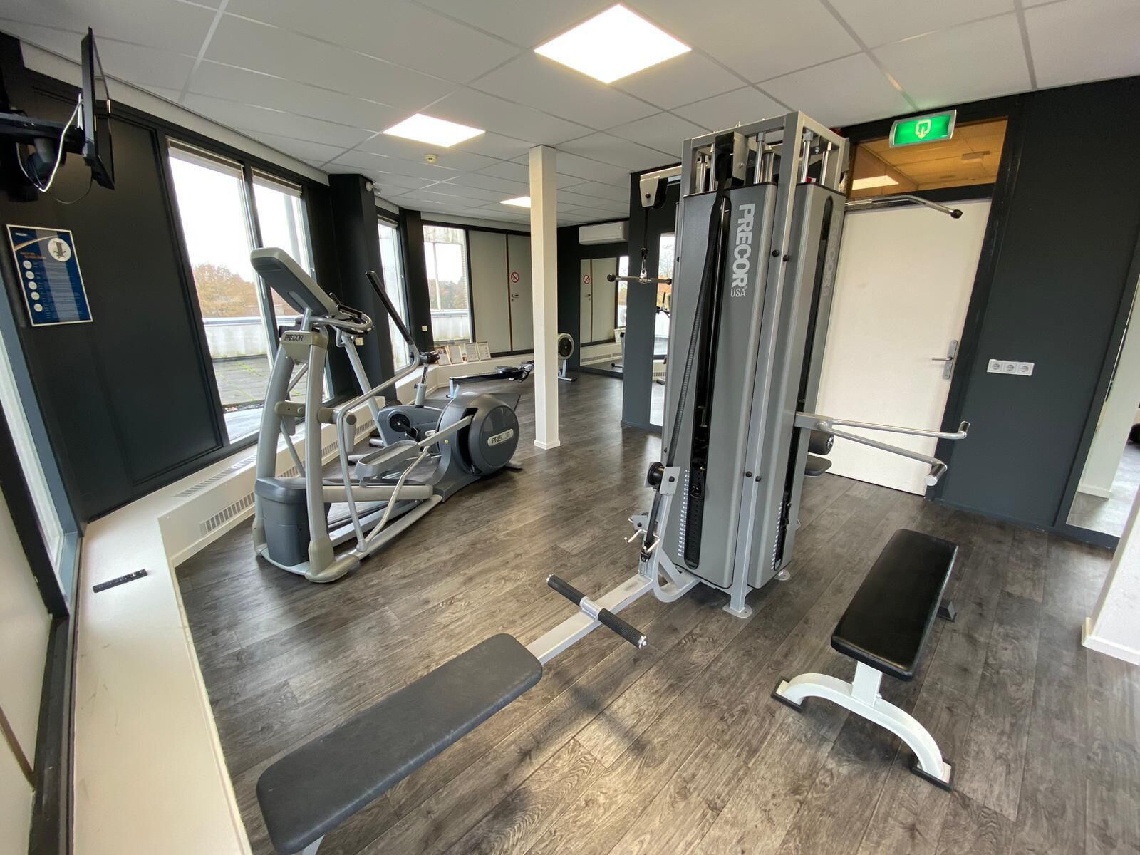 Ein Fitnessraum mit Laufbändern, Gewichten und einer Sitzbank.