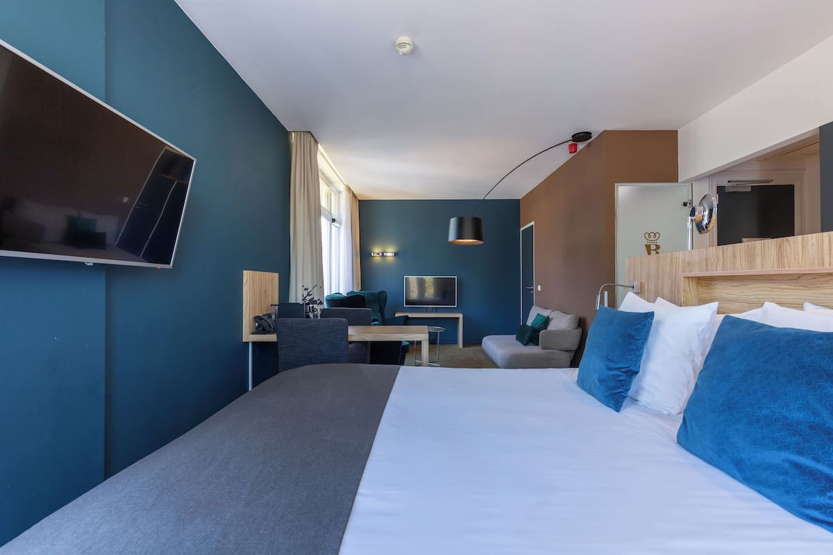 Una habitación de hotel moderna con una cama grande, un escritorio, un televisor de pantalla plana y un espejo.