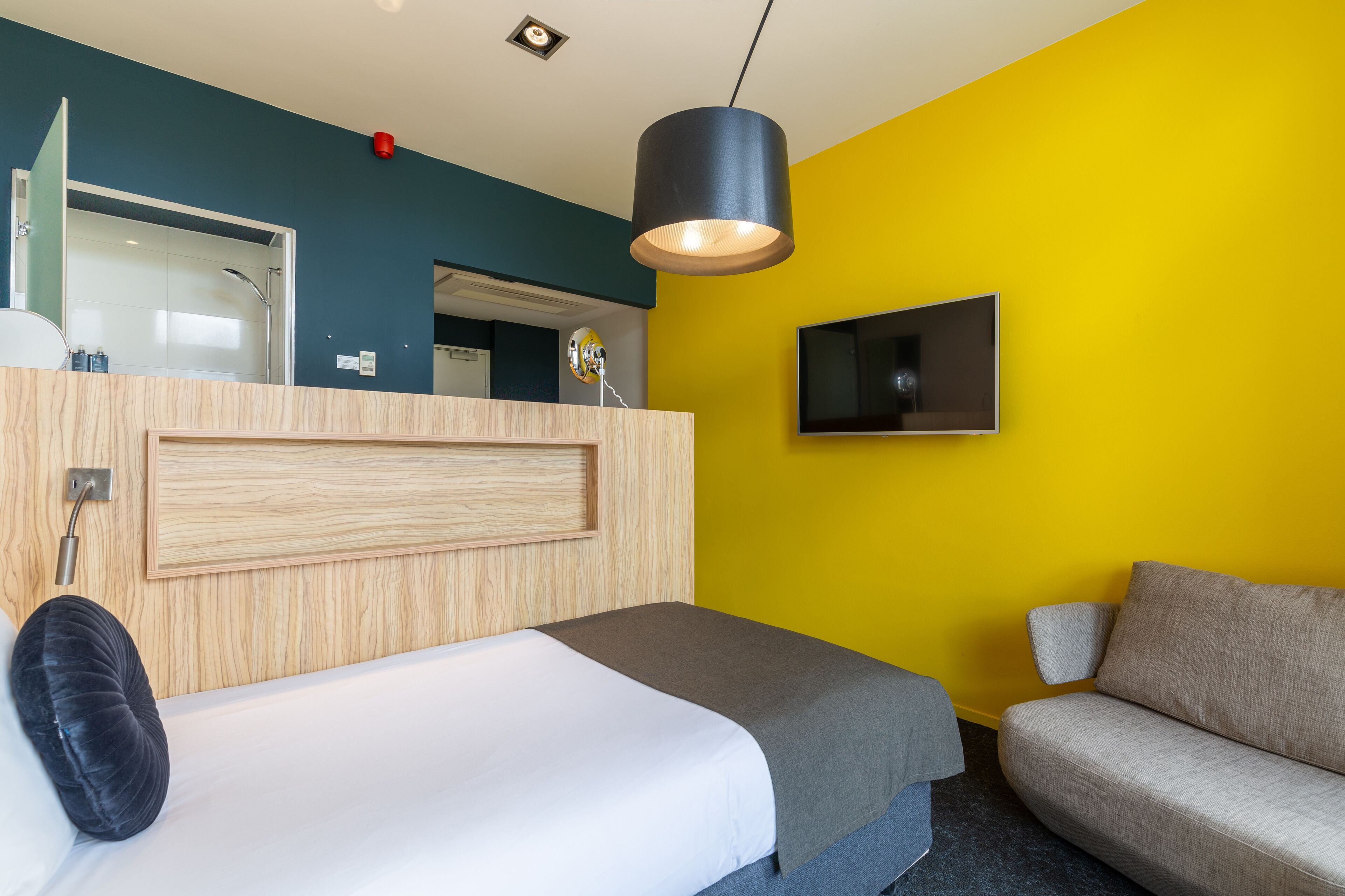 Ein Hotelzimmer mit Bett, Sofa, Fernseher und einem Badezimmer mit Dusche.
