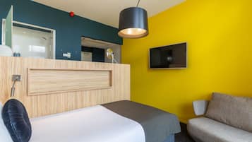 Ein Hotelzimmer mit Bett, Sofa, Fernseher und einem Badezimmer mit Dusche.
