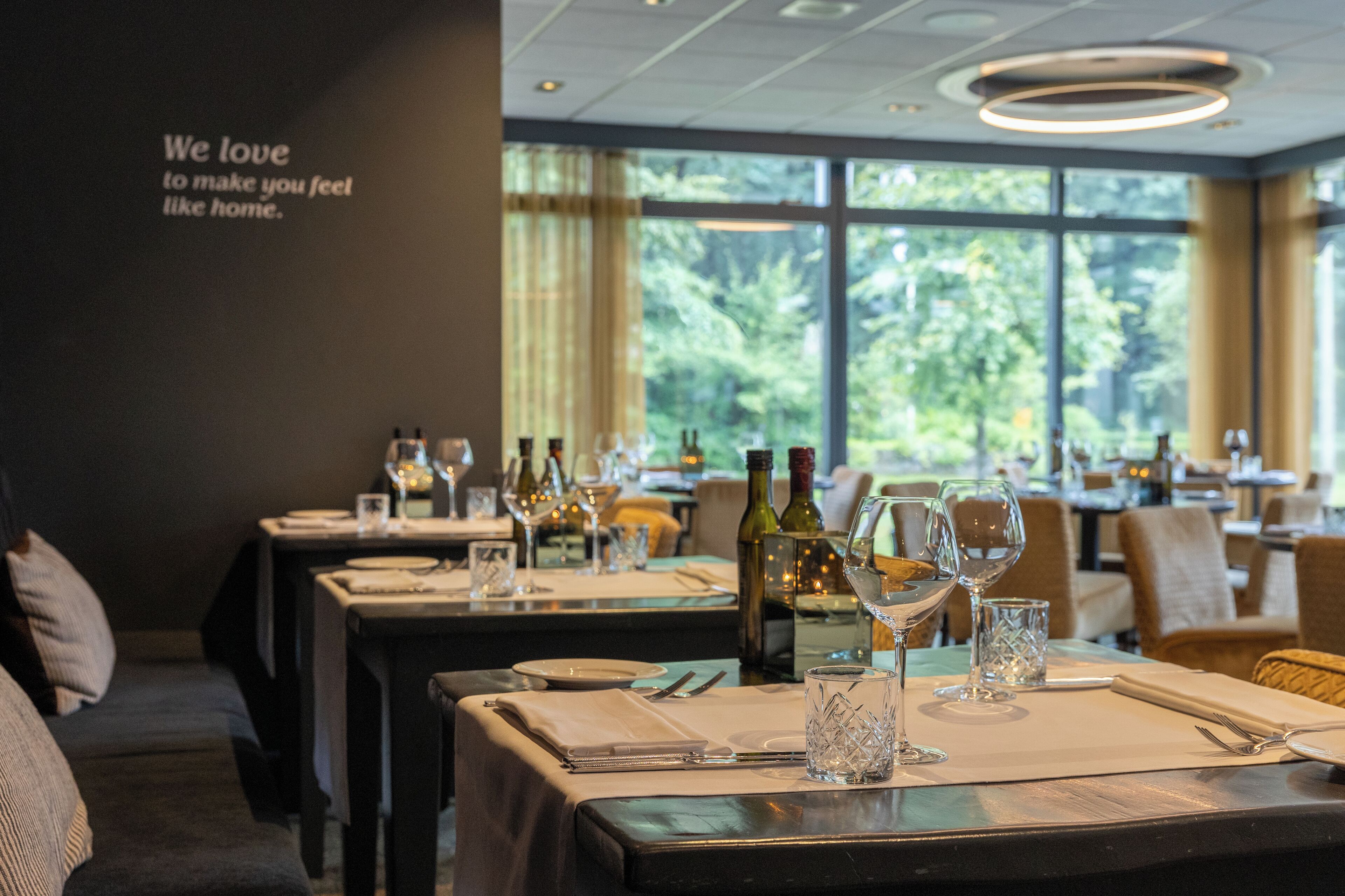 A restaurant interior with tables set for dining, wine glasses, and bottles.