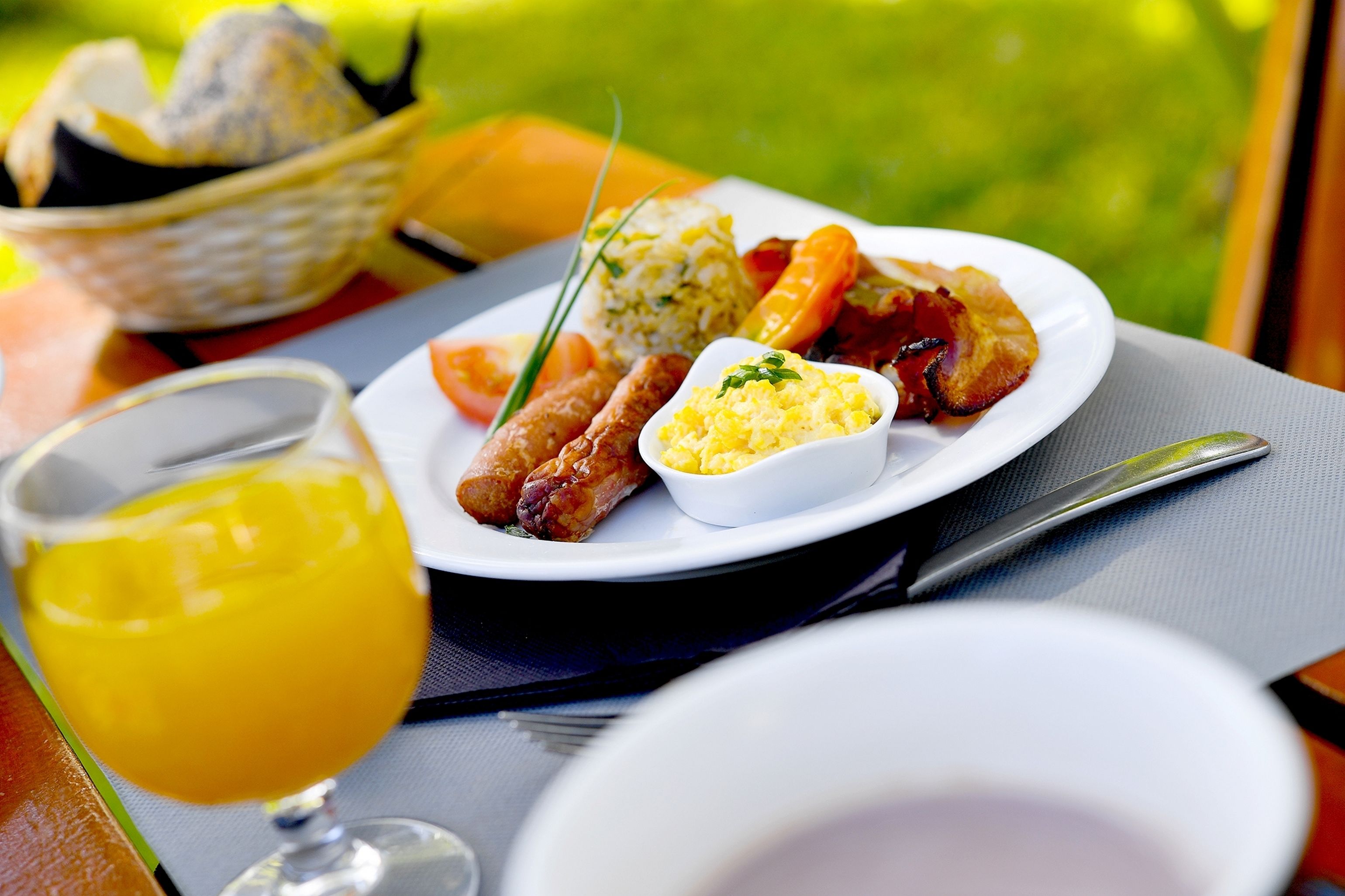 A breakfast plate with eggs, bacon, sausage, and toast, accompanied by a glass of orange juice.