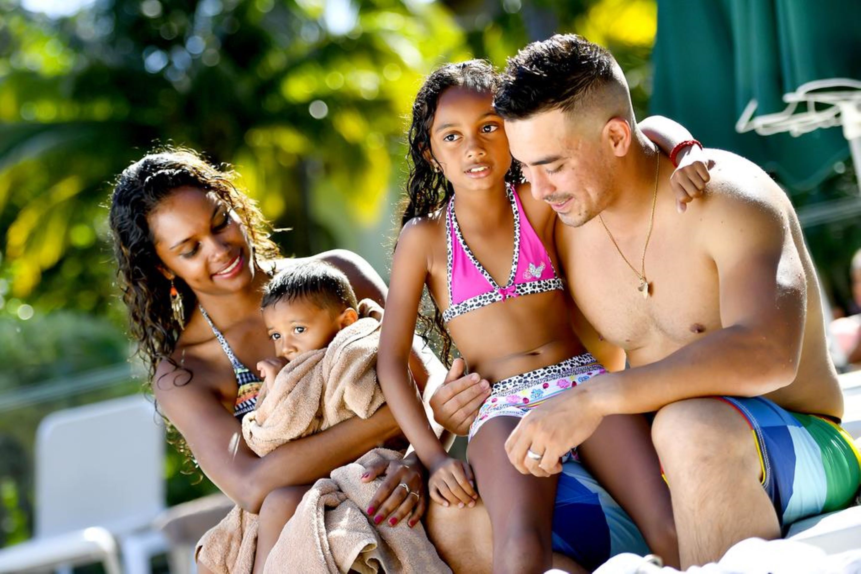 A family by a pool with a clear view of the water and greenery in the background.