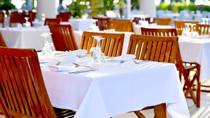 A restaurant setting with tables set for dining, featuring white tablecloths and wooden chairs. - Le Relais de L'Hermitage (Saint-Paul)