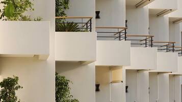 A modern multi-story building with balconies, some with plants.