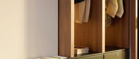 A walk-in closet with wooden doors, a green filing cabinet, and hanging clothes.