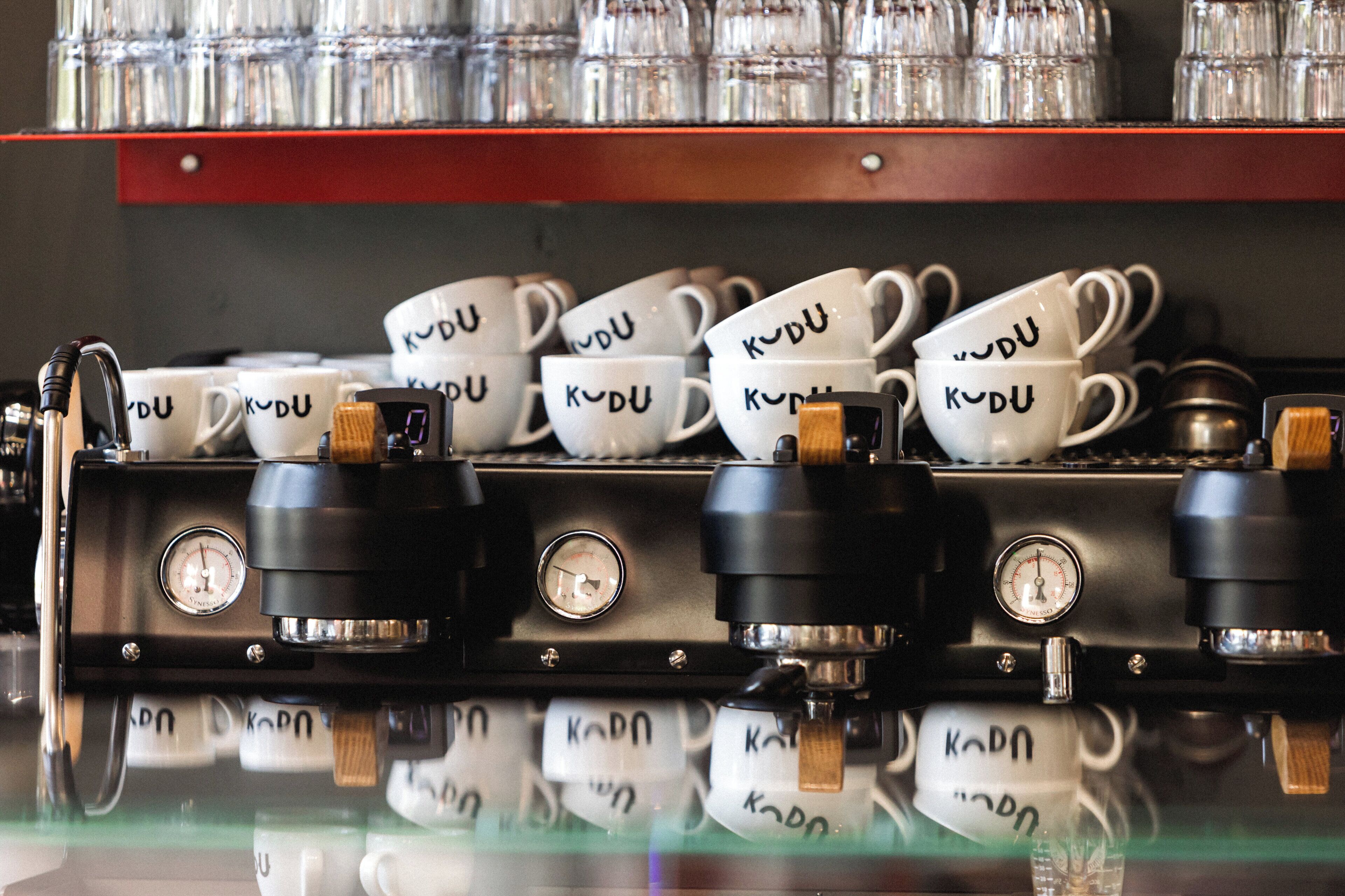 A coffee machine with multiple cups labeled "KODU" and a coffee grinder.