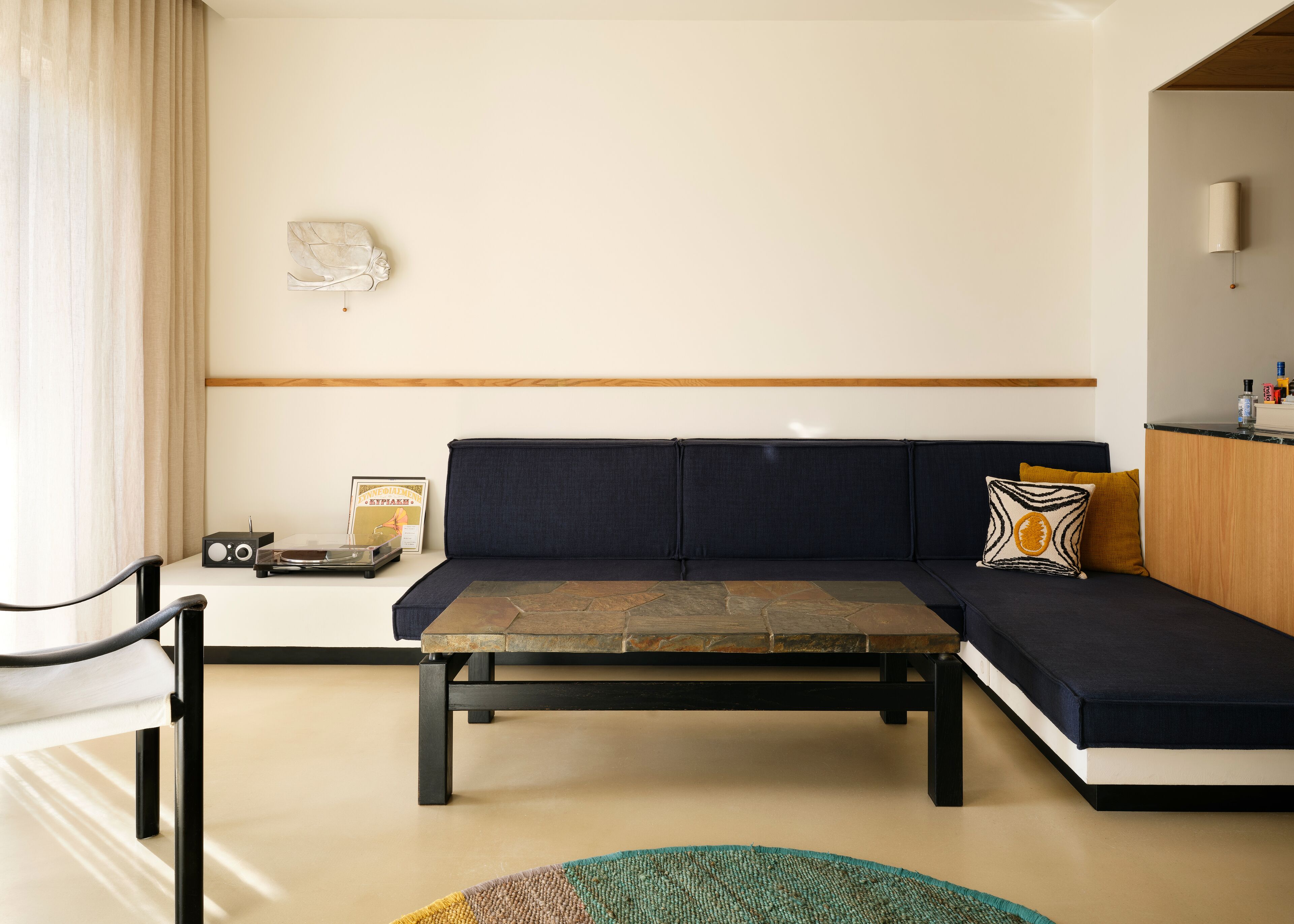 A modern living room with a dark blue sofa, a coffee table, and a small side table with a vintage radio.