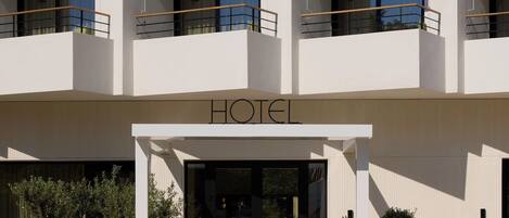A multi-story hotel with a modern facade, balconies, and a clear entrance.