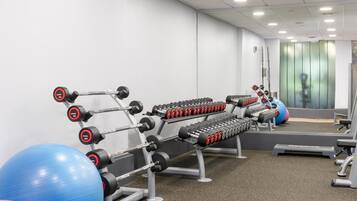 A gym with weightlifting equipment, exercise balls, and a mirror.