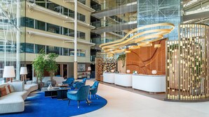 A spacious lobby with a reception desk, seating area, and a large plant. - Hilton London Heathrow Airport Hotel (Hounslow)