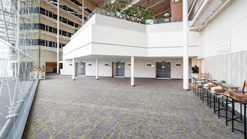 A spacious indoor area with a high ceiling, multiple levels, and a central open space with tables and chairs.