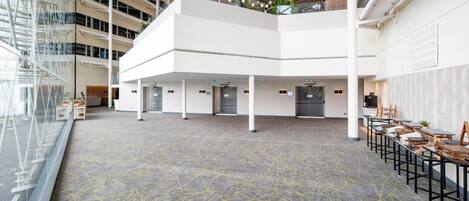 A spacious indoor area with a high ceiling, multiple levels, and a central open space with tables and chairs.