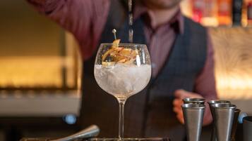 A bartender pouring a drink into a glass with ice and garnishes.