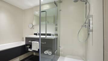 A modern bathroom with a glass-enclosed shower, a separate bathtub, and a vanity with a mirror.
