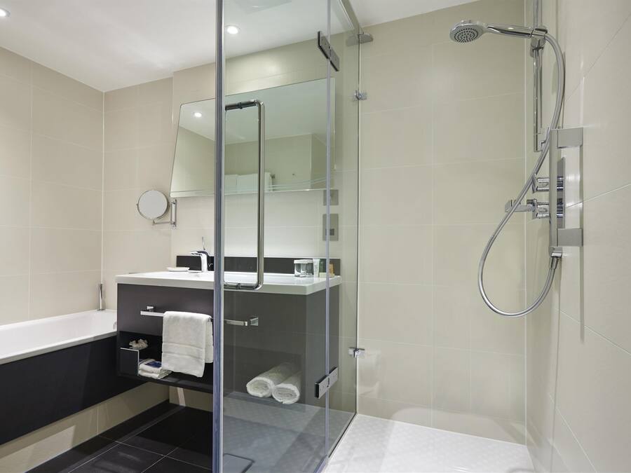 A modern bathroom with a glass-enclosed shower, a separate bathtub, and a vanity with a mirror.
