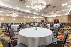 Une salle de conférence avec des tables rondes, des chaises et un lustre.