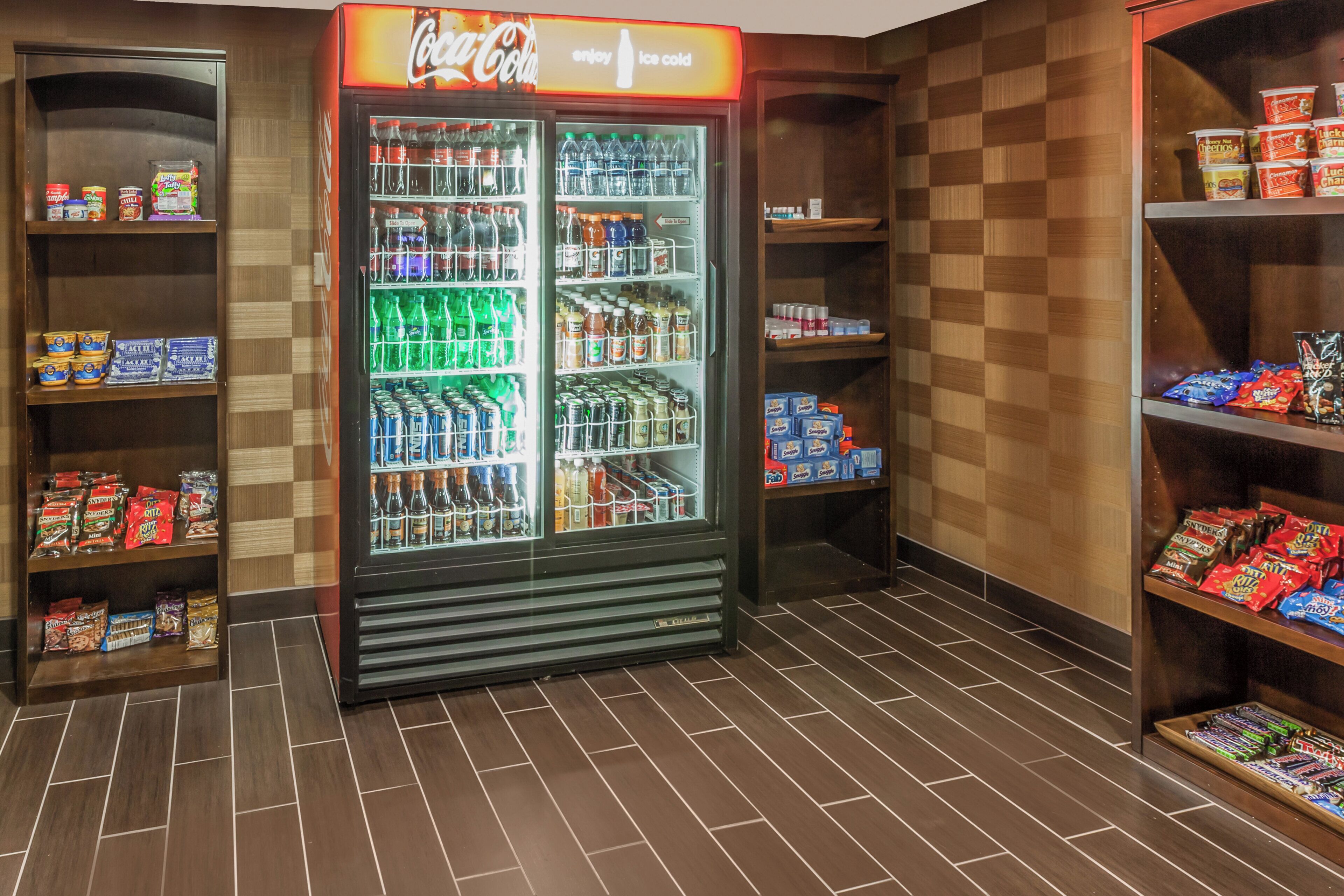 A vending machine stocked with beverages and snacks, surrounded by shelves with packaged goods.