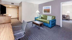 Une chambre d’hôtel avec un canapé, une petite table, une télévision et une lampe.