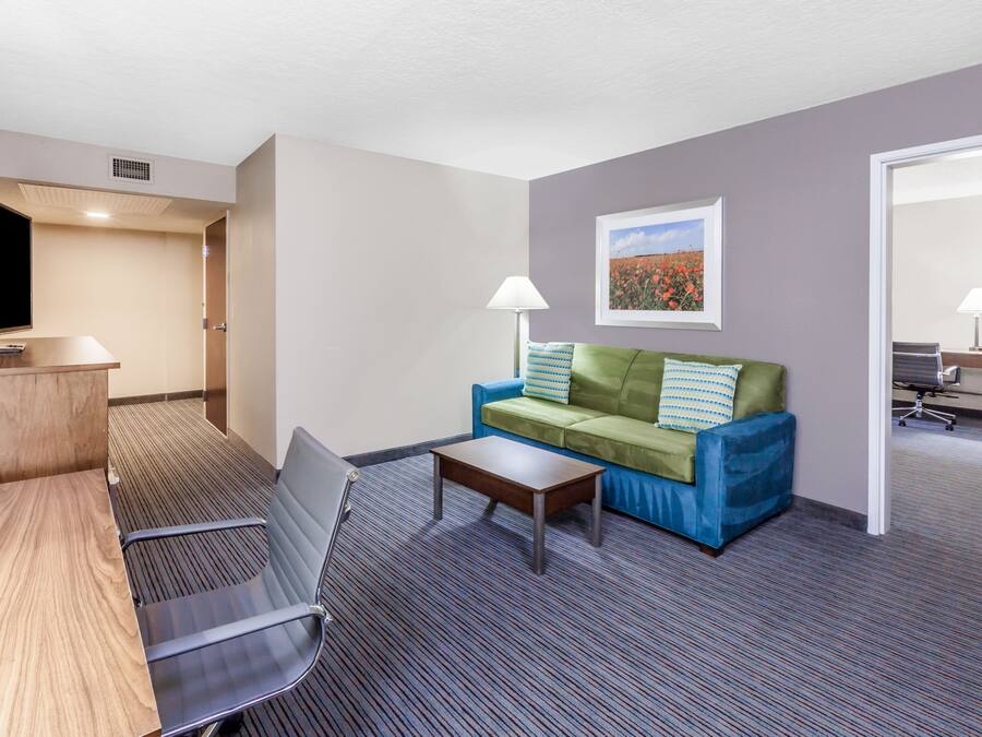 A hotel room with a sofa, a small table, a TV, and a lamp.