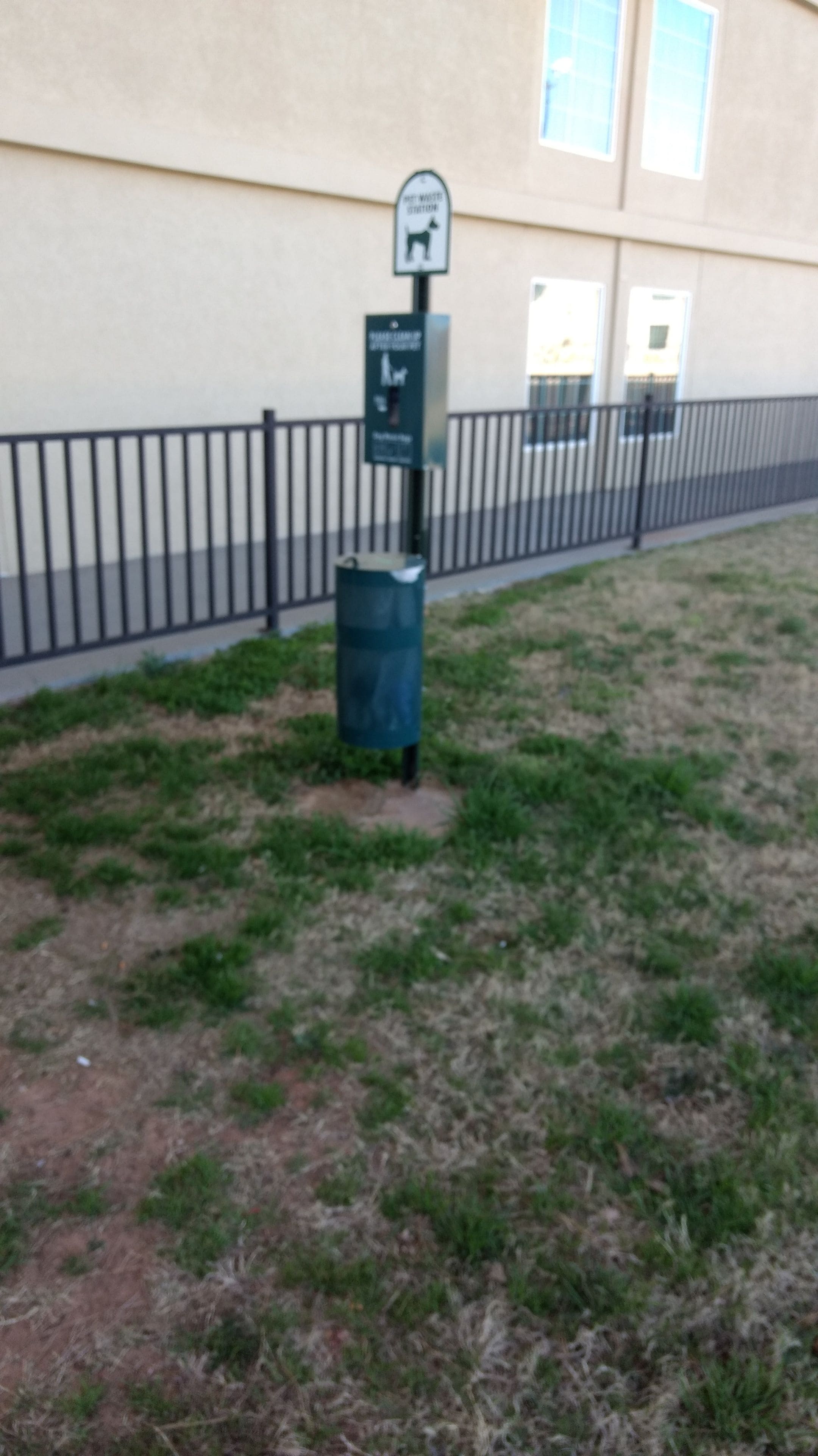 A parking area with a trash can and a sign indicating a dog waste station.