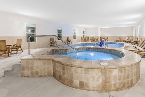 Une grande piscine intérieure dotée de plusieurs couloirs, entourée de chaises longues et de transats.