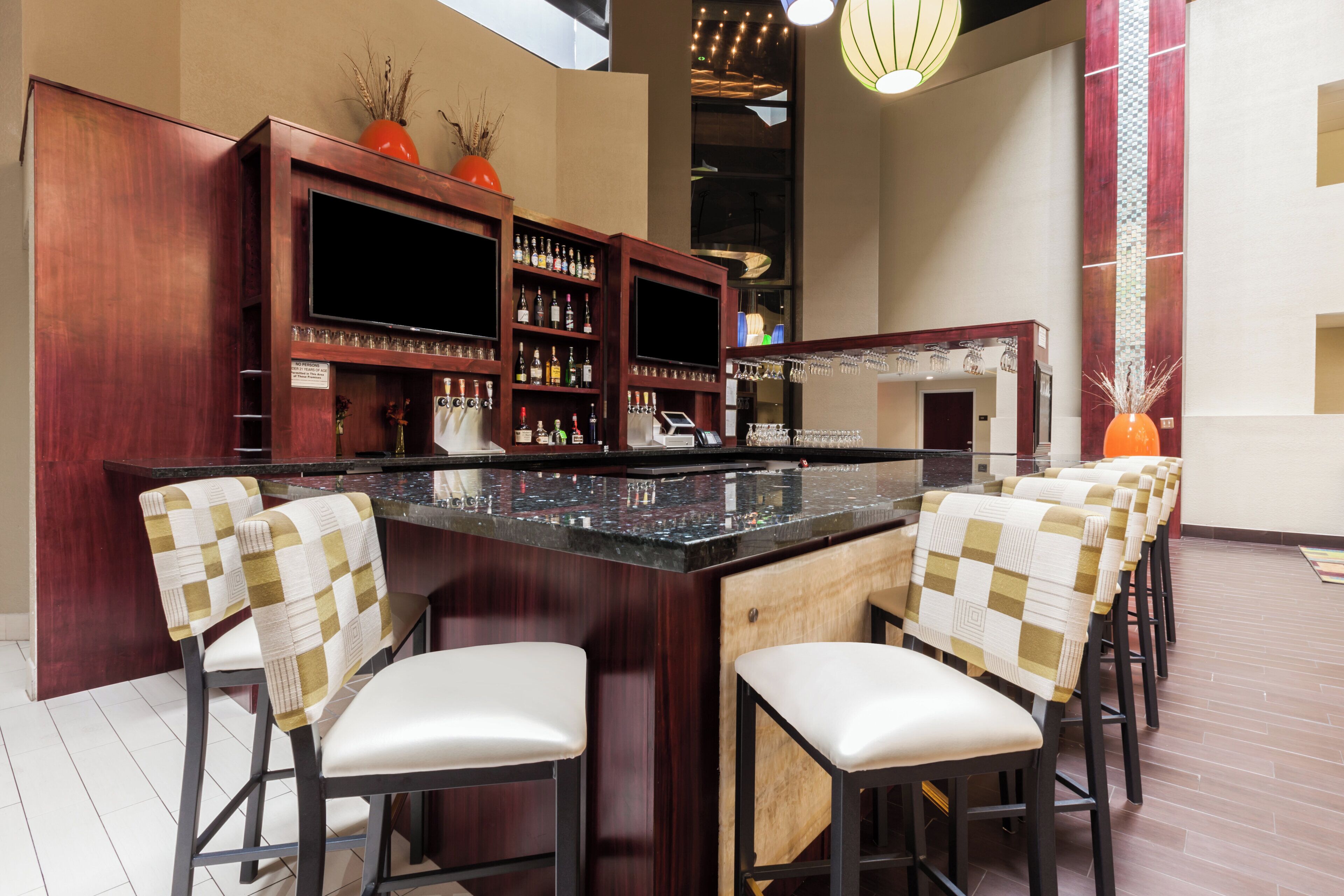 A bar area with a counter, bar stools, and shelves of bottles.